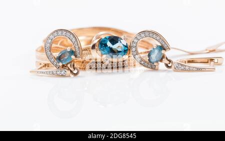 Gold earrings in the shape of a horseshoe and a delicate ring with large Topaz Stock Photo