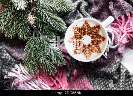 Coffee with a snowflake pattern on a warm woolen plaid background. Top view Stock Photo