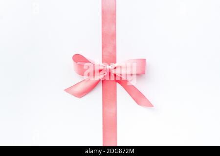 Pink ribbon with bow isolated on white. Top view, copy space Stock Photo