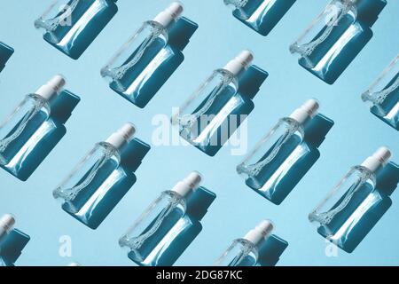 Trendy Pattern of sprays with alcoholic antiseptic, sanitizers on a blue background. Flat lay, hard shadow from the sun. Anti-virus protection concept Stock Photo