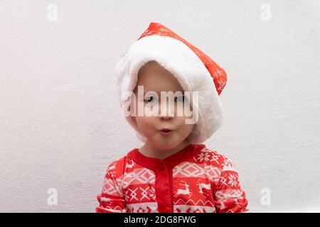 Toddler at red Santa hat surprised and excited waiting Christmas and New Year Stock Photo