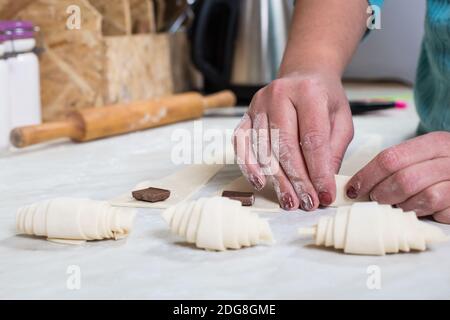 Hands making croissants with chocolate on a lifestyla kitchen. Stock Photo
