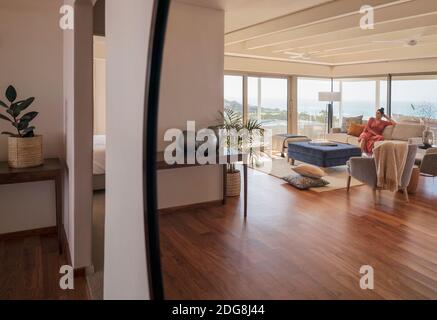 Reflection in mirror of woman relaxing on luxury living room sofa Stock Photo