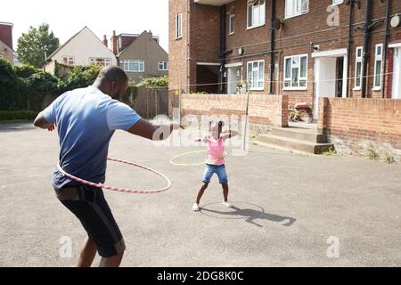 Father and daughter playing with plastic hoops in sunny neighborhood Stock Photo