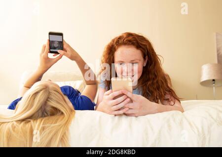 Preteen girl friends using smart phones on bed Stock Photo