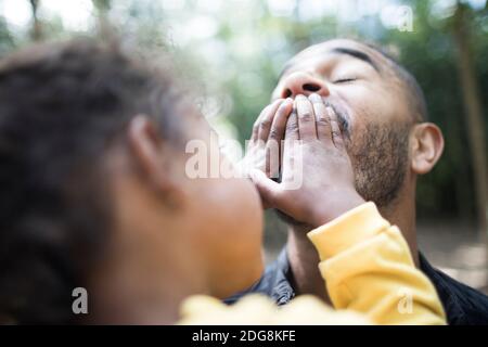 Playful daughter covering mouth of father Stock Photo