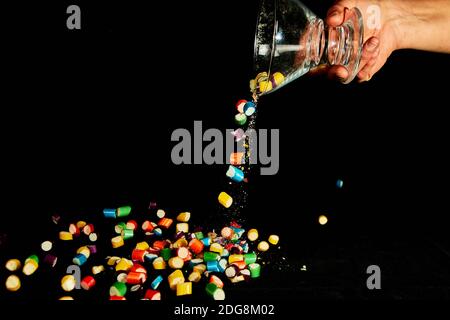 sugar candies falling from glass container on black table background. Empty space for text Stock Photo