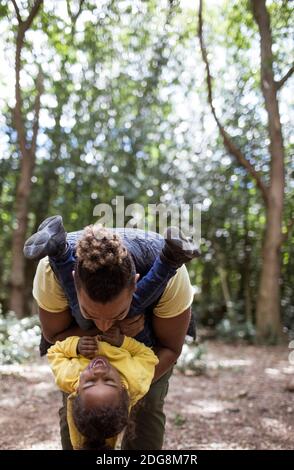 Playful father holding daughter upside down in woods Stock Photo