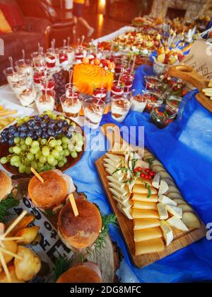 Different types of appetizers on the buffet. Delicious and interesting food. Natural cheeses are worn on a wooden board Stock Photo