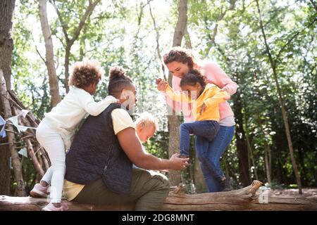 Happy family playing on fallen log in summer woods Stock Photo