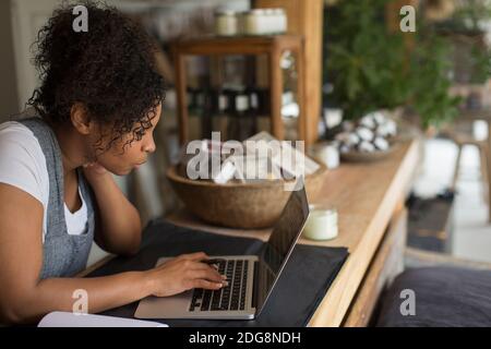 Female shop owner using laptop at shop counter Stock Photo