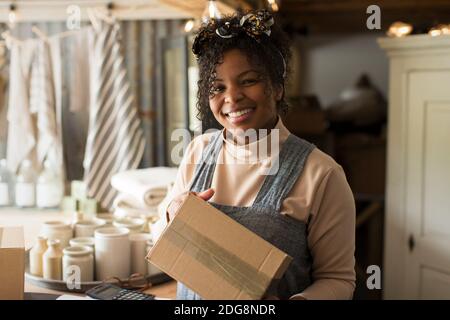 Portrait happy female shop owner with package Stock Photo