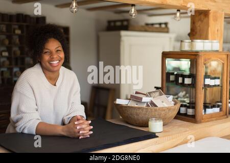 Portrait happy friendly female shop owner at counter Stock Photo