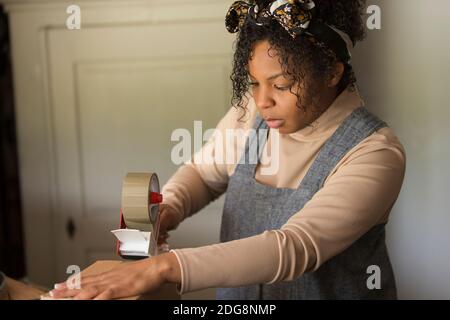 Female shop owner taping box for shipping Stock Photo