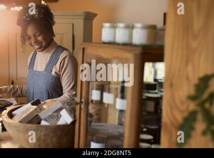 Smiling female shop owner working at counter Stock Photo