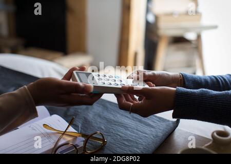 Close up shop owner holding credit card reader for customer Stock Photo