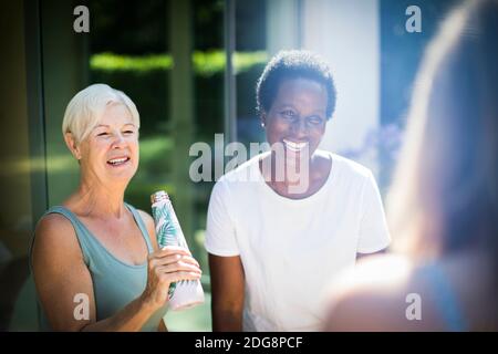 Happy senior women friends laughing on sunny summer patio