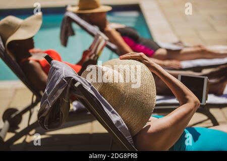 Senior women friends sunbathing at sunny summer poolside Stock Photo