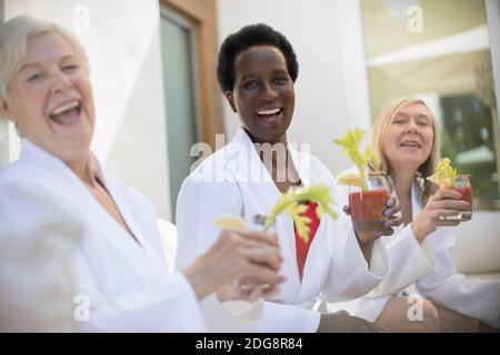 Portrait happy senior women friends drinking bloody mary cocktails Stock Photo
