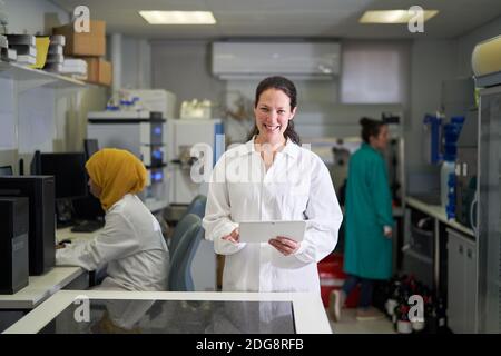 Portrait happy female scientist with digital tablet in laboratory Stock Photo