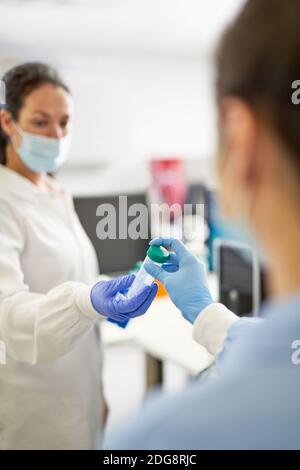 Female scientists in face masks working in laboratory Stock Photo