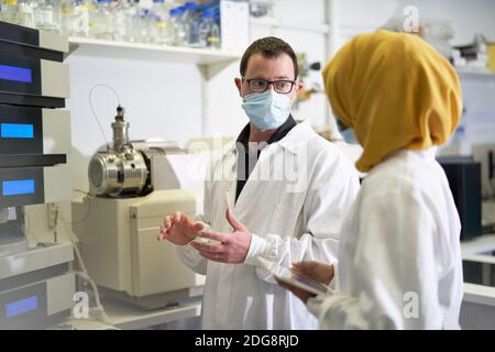 Scientists in face masks talking in laboratory Stock Photo