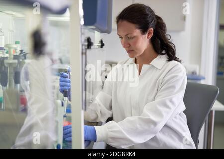 Focused female scientist in lab coat working in laboratory