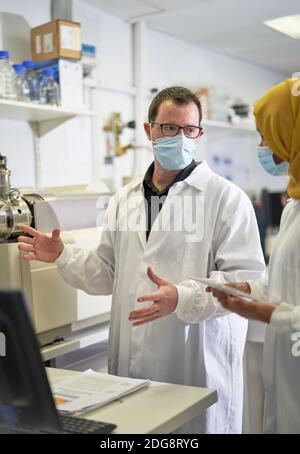 Scientists in face masks talking in laboratory Stock Photo