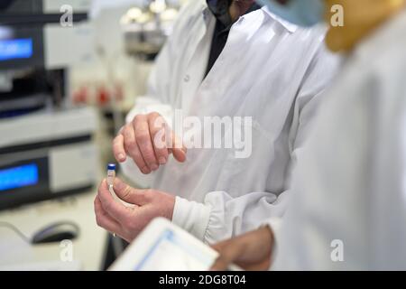 Close up scientists examining vial in laboratory Stock Photo