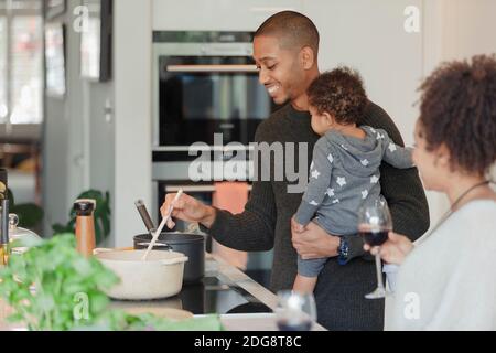 Happy couple with baby daughter cooking dinner in kitchen Stock Photo