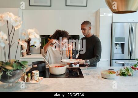 Couple with baby daughter cooking spaghetti in kitchen Stock Photo