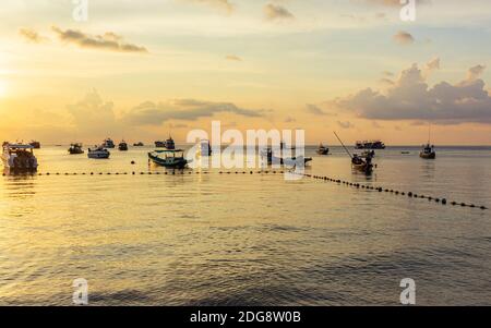 Koh Tao, Thailand: April 23 2019: island village boat pier, evening sunset time at beach, long tail boats in sea waiting for sun going down Stock Photo