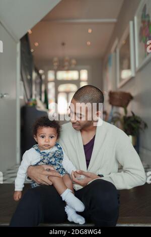 Father holding cute baby daughter in corridor at home Stock Photo