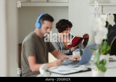 Couple reading and working from home at laptop Stock Photo