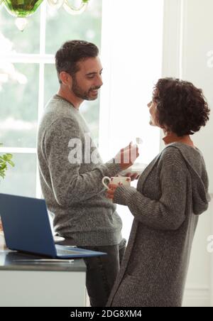 Happy couple talking and working from home in kitchen Stock Photo