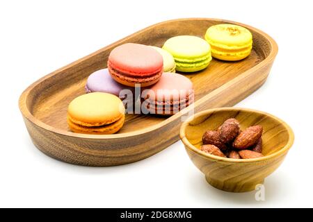 Sweet macarons in wooden tray and almonds in wooden bowl Stock Photo