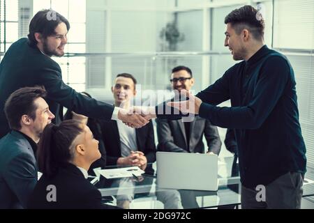 smiling business people shaking hands over an office Desk Stock Photo