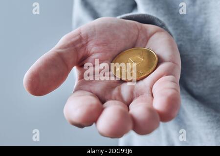 Hand offering Ethereum cryptocurrency coin, close up with selective focus Stock Photo