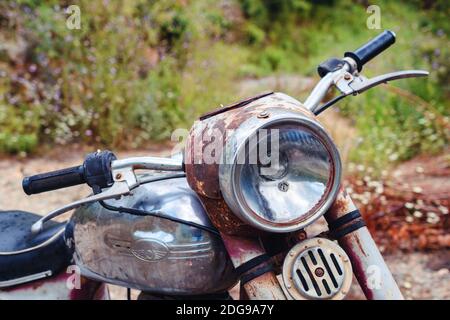 The thrown abandoned old rusty brown vintage motorcycle in the forest ...