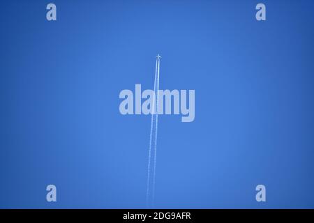 Airline jet plane against blue sky leaving behind a vapour trail or contrail  Photograph taken by Simon Dack Stock Photo