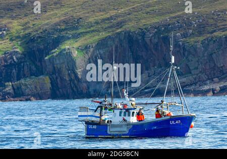 Fishing boat off Ullapool in Scotland with two fishermen on a blue boat, fishing inshore with creels.  Pre-Brexit. Horizontal.  Space for copy. Stock Photo