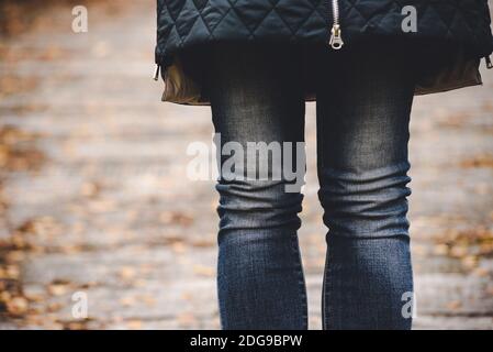 Thin female legs in blue jeans against the background of an autumn landscape Stock Photo