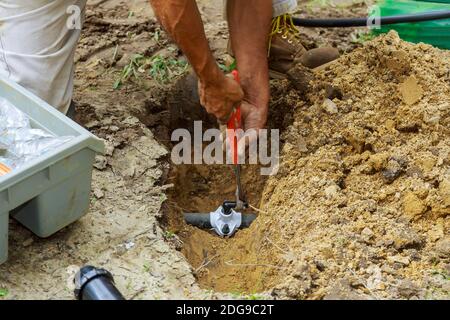 Man Working with Pipes in Ground while Installing a New Underground Sprinkler System Stock Photo