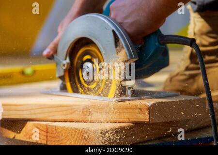 Carpenter using circular saw for cutting wooden boards with hand power tools. Stock Photo