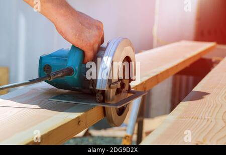 Cutting wood beam using an electrical chainsaw and professional tools Stock Photo