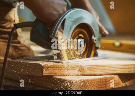 Close-up of a carpenter using a circular saw to cut a large board of wood Stock Photo