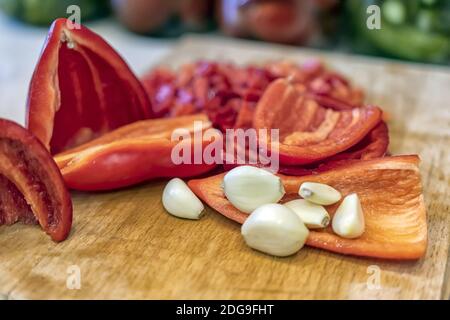 Peeled garlic and chopped red bell pepper lie on a cutting Board Stock Photo