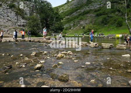 People Crossing The River Dove Across The Stepping Stones At Dovedale In The Peak District Derbyshire England UK Stock Photo