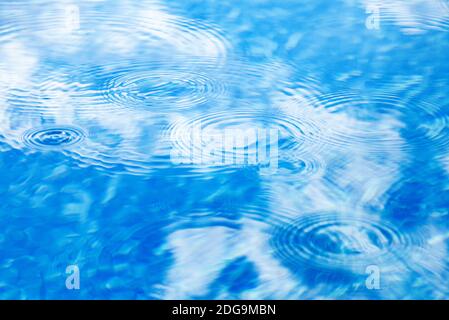 Raindrops on pool blue water surface. Blue water texture as background. Stains circles on the water from rain Stock Photo