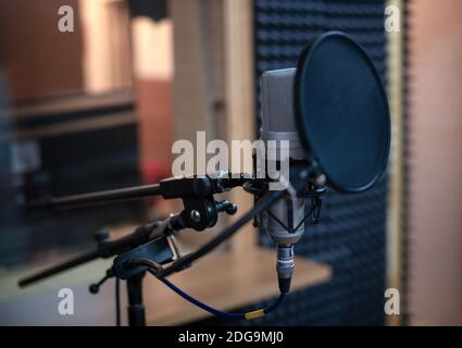 Voice microphone with shock mount and pop filter on professional tripod in audio recording studio. Stock Photo